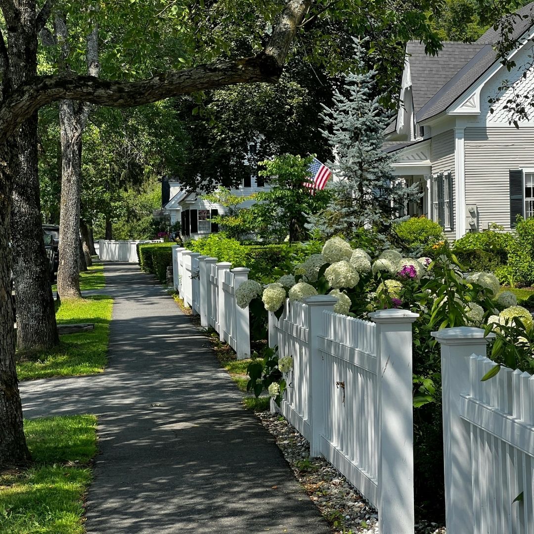 view down neighborhood street with white vinyl fencing